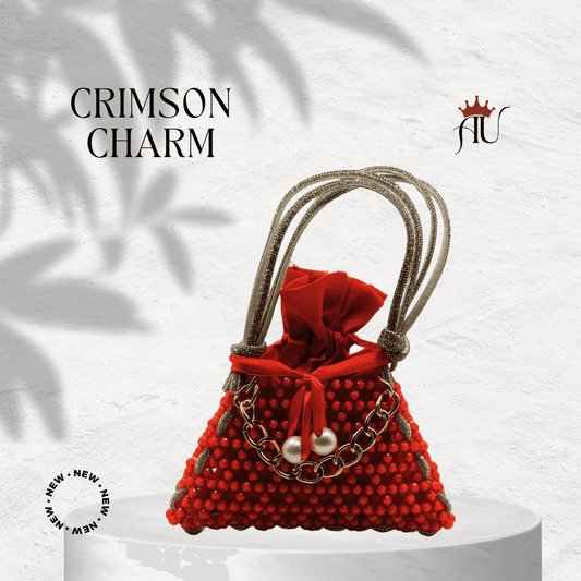 Crimson Charm red handbag with textured details, gold chain, pearl embellishments, and shimmering handles on a white pedestal