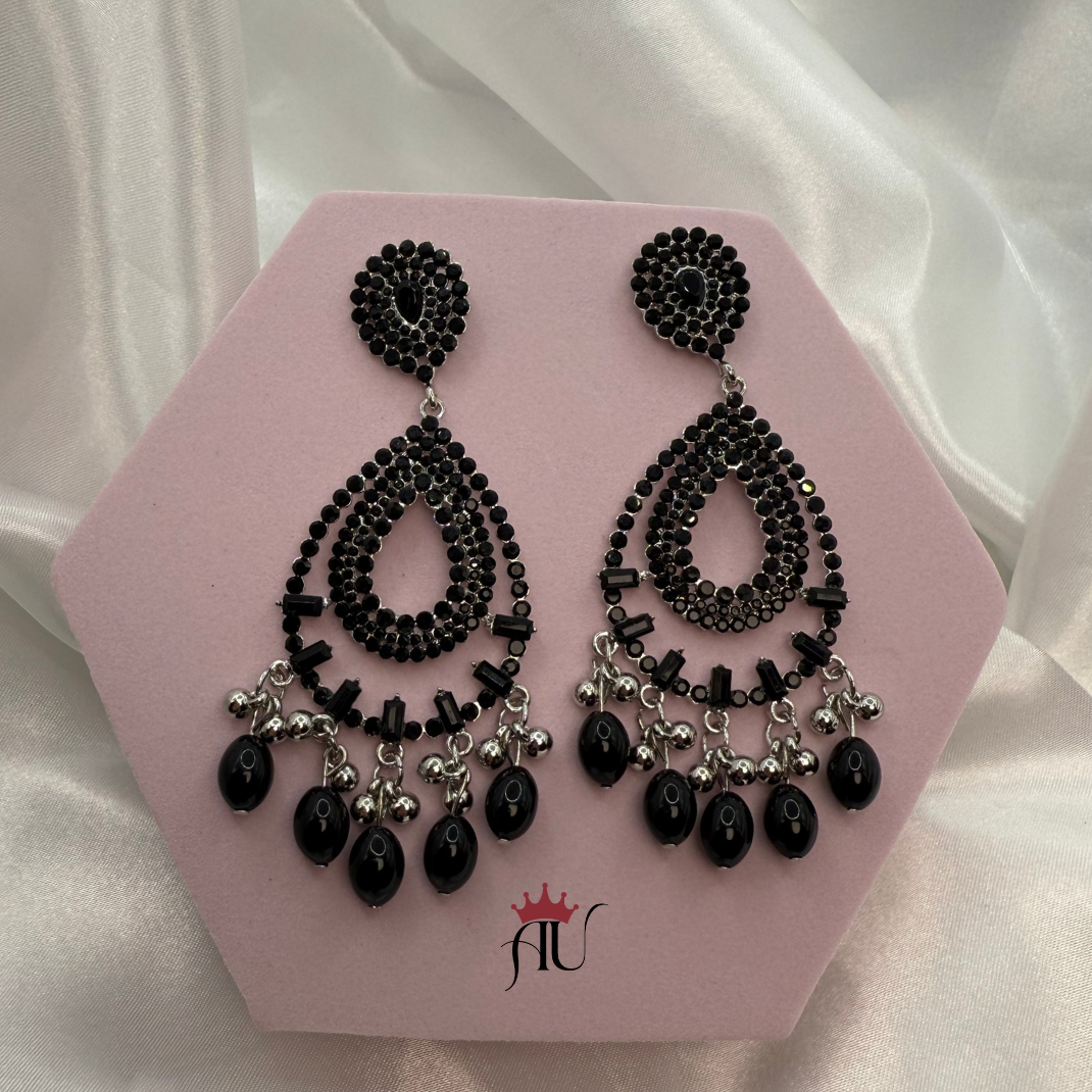 Black beaded earrings on a pink hexagonal card with a white background